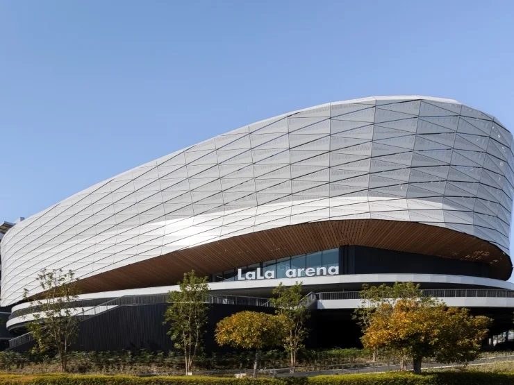 la la arena tokyo-bayの外観。楕円形の会場が斜め上に向かって伸びている。正面には、 La La arenaの大きな切り文字が設置されている。