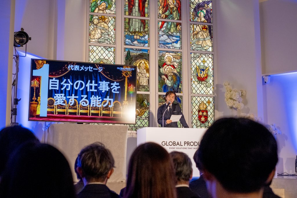 ステンドグラスの前で、登壇者がスピーチをしている入社式の様子。