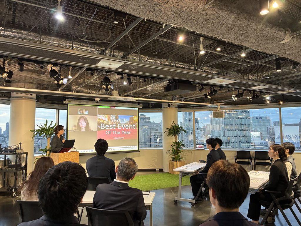 オンライン参加者と画面をつなぎながら「GP2025 Best Event Of The Year」を紹介する様子。会場の参加者もスクリーンに注目し、対面とオンラインを組み合わせたプログラムが進行している。